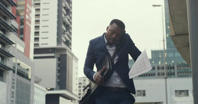 A busy corporate businessman on a phone call drops his laptop while walking in the city. Clumsy, silly and young entrepreneur multitasking while networking on a mobile device and makes a mistake