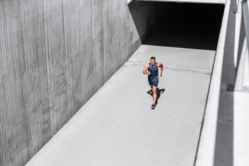 fitness, sport and healthy lifestyle concept - young man running out of tunnel