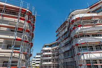 Moderne, noch einger&uuml;stete Wohnh&auml;user mit Etagenwohnungen in einem Neubaugebiet bei sonnigem Wetter und blauem Himmel