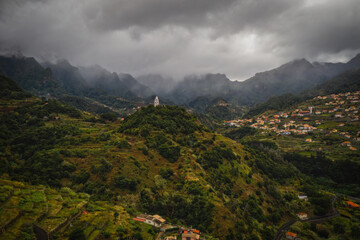 Fototapeta na wymiar Sao Vicente or San Vicente, Madeira, Portugal - October 2021: The fragment view of Sao Vicente village from mountain. Catholic church on front. Aerial drone picture