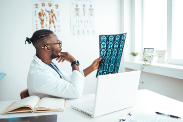 Medical experts studies the EEG condition of the patient. Revealing brain deformations. Qualified smart concentrated radiograph working at the office while holding computed tomography photo