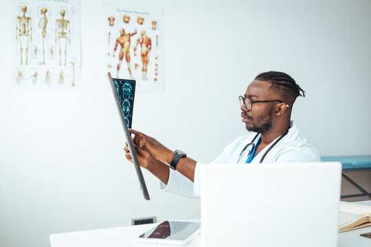 Closeup portrait of intellectual man healthcare personnel with white labcoat, looking at full body x-ray radiographic image, ct scan, mri, isolated hospital clinic background. Radiology department