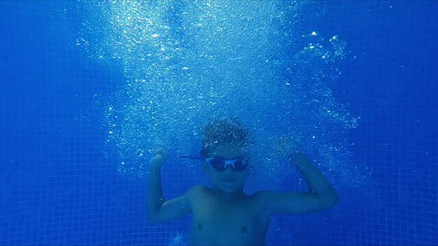 funny little boy jumping in the pool and dancing underwater shot 