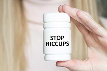 STOP HICCUPS inscription on a white jar with medicine in the doctor's hand, medical concept