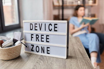 digital detox and leisure concept - close up of device free zone words on light box, gadgets in...
