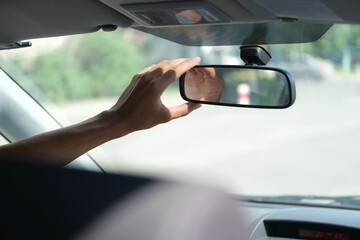 hand of the driver who adjusts the rear view mirror in the car