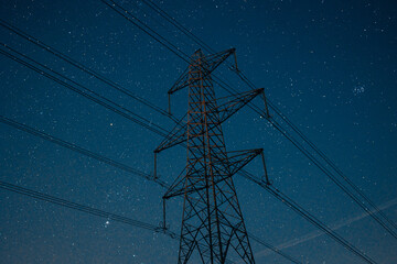 Newburn UK: March 2022: Looking up at electricity pylons on a clear starry night. Blue hour moody colours