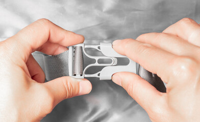 Fototapeta premium Gray plastic buckle. Fasten the plastic clip. Women's hands fasten a plastic buckle.