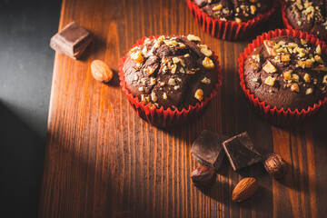 Homemade chocolate muffins or cupcakes sprinkled of nuts on a wooden board