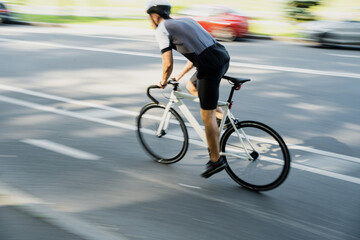 Obraz premium In motion blurred, a male athlete in gear rides a bike for highway training