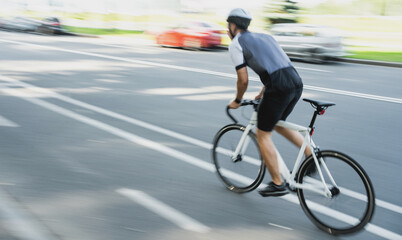 A blurry photo in motion, a man on a road bike in a helmet riding in cycling clothes