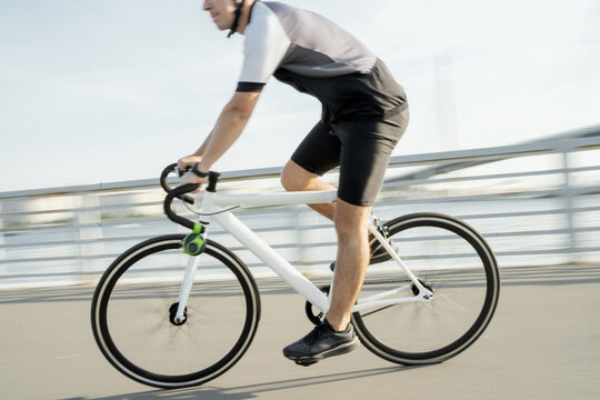 A photo in motion, a man on a road bike in a helmet riding in cycling clothes