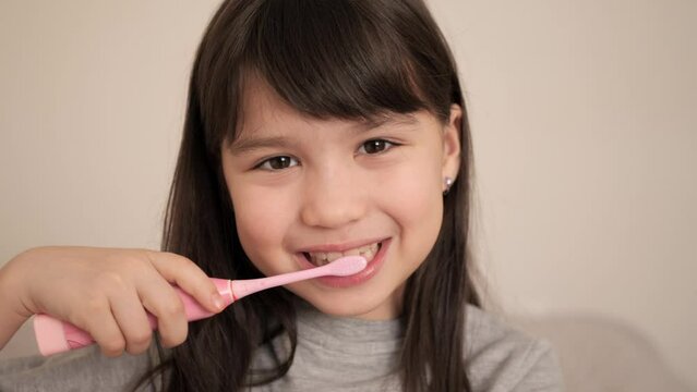 Little girl is brushing teeth with toothbrush at home. Cute kid smile. Children daily healthcare routine, dental hygiene.