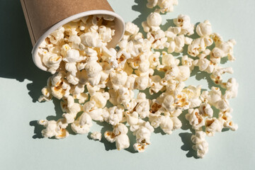 Scattered salt popcorn from craft paper cup. Concept of cinema or watching TV.