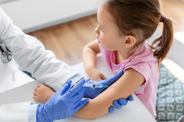 medicine, healthcare and vaccination concept - doctor or pediatrician with syringe making vaccine...