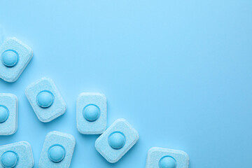 Water softener tablets on light blue background, flat lay. Space for text