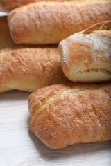 Tasty baguettes on white wooden table, closeup
