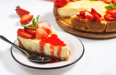 Piece of cheesecake with fresh strawberries jam and mint. Tasty homemade cheesecake on white background.