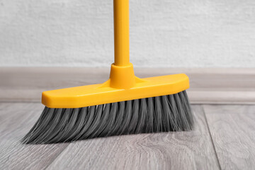 Sweeping wooden floor with plastic broom, closeup