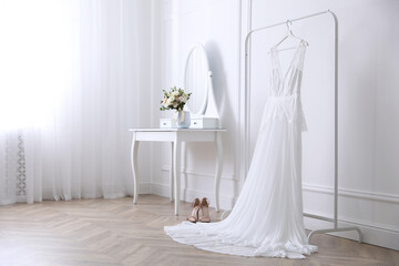 Elegant wedding dress hanging on rack indoors