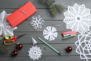 Flat lay composition with paper snowflakes on grey wooden table
