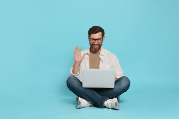 Handsome man with laptop on light blue background