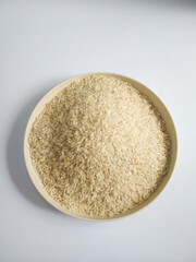 A plate of white raw rice, on a white background top view