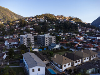 Obraz premium Aerial view of the city of Teresópolis. Mountains and hills with blue sky and many houses in the mountain region of Rio de Janeiro, Brazil. Drone photo. Araras, Teresópolis. Sunny day. Sunset