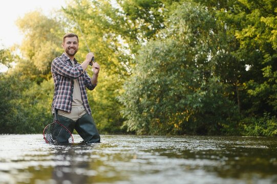 Fisherman catches a trout on the river in summer