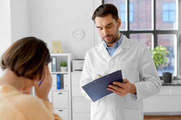 Fototapeta premium medicine, healthcare and people concept - male doctor with clipboard and fe male patient having health problem at hospital