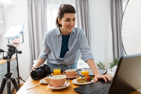 blogging, photographing and people concept - happy smiling female food blogger or photographer with laptop and camera in kitchen at home