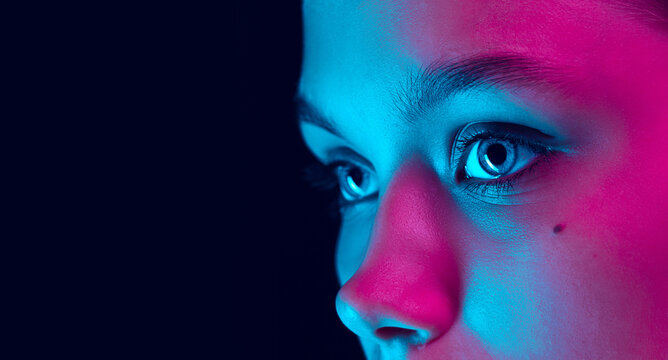 Close up eyes of beautiful young girl looking away in pink neon light. Concept of cosmetics, makeup, natural and eco treatment, skin care.