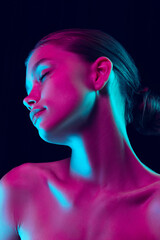 Portrait of tender young woman posing isolated over dark background in neon light. Concept of beauty, art, cosmetics and youth