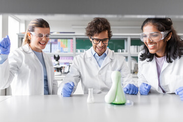 science research, work and people concept - international team of scientists with chemicals working...