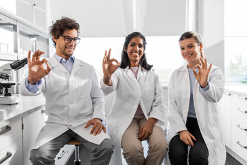 Fototapeta na wymiar science, work and people concept - international group of happy scientists in laboratory showing ok gesture