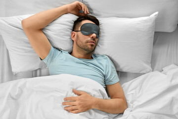 people, bedtime and rest concept - man in eye mask sleeping in bed at home, top view
