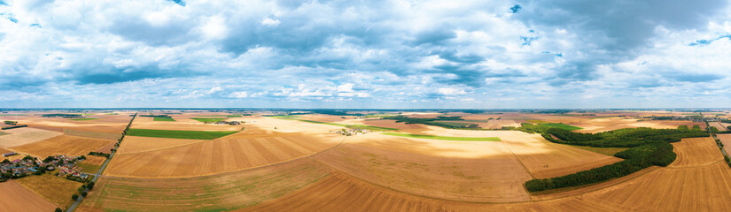 Fototapeta na wymiar A beautiful panorama from the air of a blue sky with clouds and from below a town among green fields. beautiful panorama of Arges county landscape in spring. France. Aerial. Drone 4k.