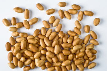 Cleaned, salted peanuts on white background. Peanuts spread on white background, shot from above.