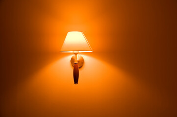 Close up of a classic illuminated lamp on the wall. Beautiful wall scone with lamp shade.