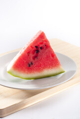 A triangular slice of fresh watermelon on a white plate. Close up of juicy and nutritious watermelon.
