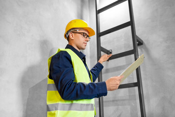 architecture, construction and building concept - male builder or worker in helmet and safety west...