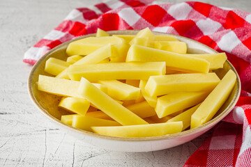 peeled potatoes sliced for french fries on a white background