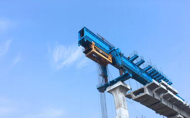 A view of construction site of huge bridge. A massive concrete bridge sections has been installed on column by a suspended crane.