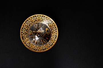 Defocused lens ball on a golden metal tray, isolated on black background.