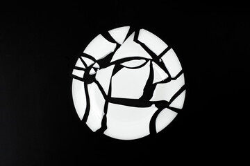 Fototapeta na wymiar Broken white plate with arranged pieces isolated on black background