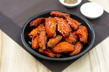 Stir fried chicken fillet with sauce is placed in a black plate on wooden table, Thai food