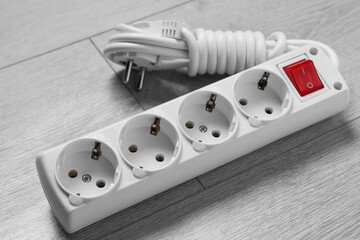 Power strip on wooden floor, closeup. Electrician's equipment