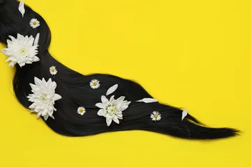 Fotobehang Lock of healthy black hair with flowers on yellow background, top view. Space for text © New Africa