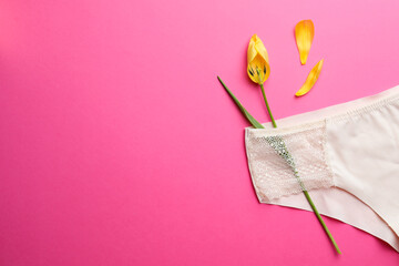 Yellow tulip and panties on pink background, top view with space for text. Menopause concept
