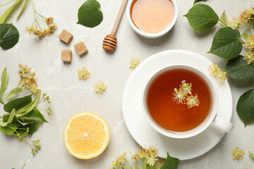 Flat lay composition with tasty tea and linden blossom on light grey marble table